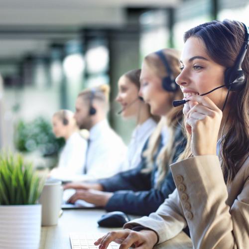 Female,Customer,Support,Operator,With,Headset,And,Smiling,,With,Collegues